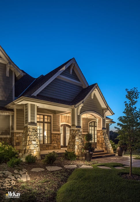 Thoughtful fixture placement at the base of the home lets the light gently crawl up the stonework and creates interesting shadows while evenly illuminating the front peaks. Click to learn more about the outdoor lighting design... | McKay Landscape Lighting - Omaha, Nebraska