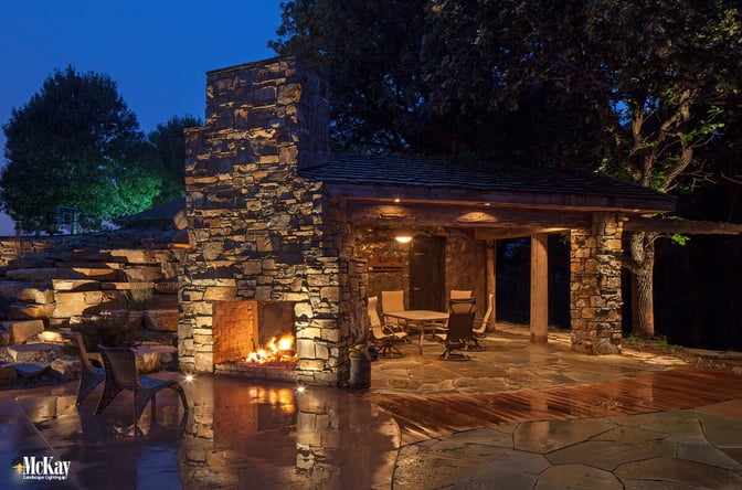 Many fireplaces are made of natural stone, uplighting the stonework creates unique shadow effects. The light gently crawls up the fireplace not to over overpower it or take away from the effect the fire brings. Click to read more... | Outdoor Stone Fireplace Lighting | McKay Landscape Lighting - Omaha Nebraska 